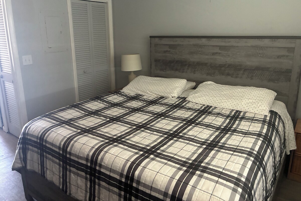A bedroom with a bed, a nightstand, a lamp, and a closet.