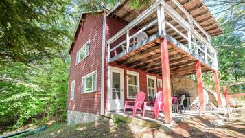 A red wooden cabin with a covered porch and pink chairs.