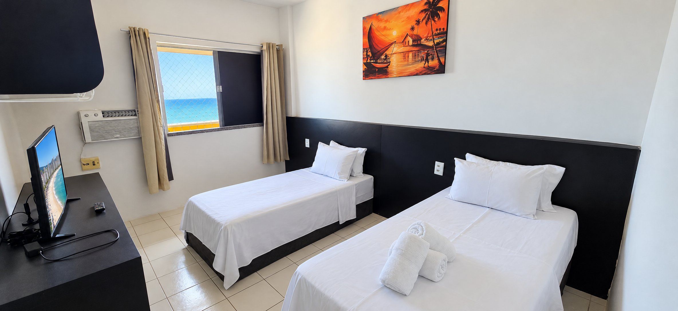 A hotel room with two beds, a TV, and a painting.