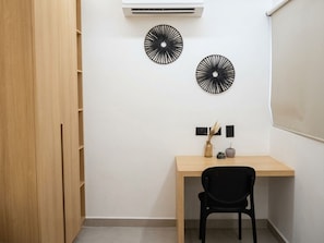 Una habitación con un escritorio de madera, dos adornos en la pared, una silla negra y un armario.