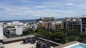 Eine Dachterrasse mit Pool, Sitzgelegenheiten im Freien und Blick auf die Stadt und das Meer.