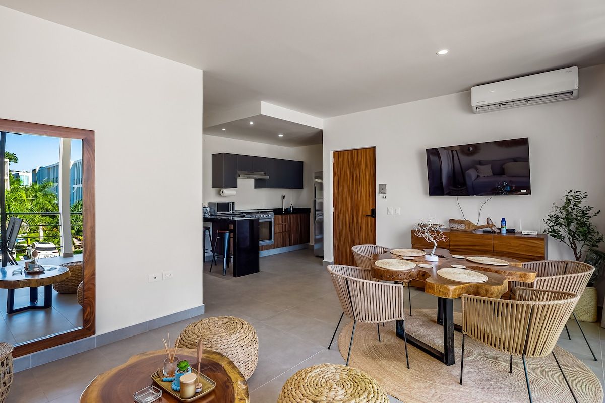 A modern interior with a dining area, kitchen, and a TV mounted on the wall.