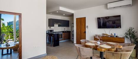 A modern interior with a dining area, kitchen, and a TV mounted on the wall.