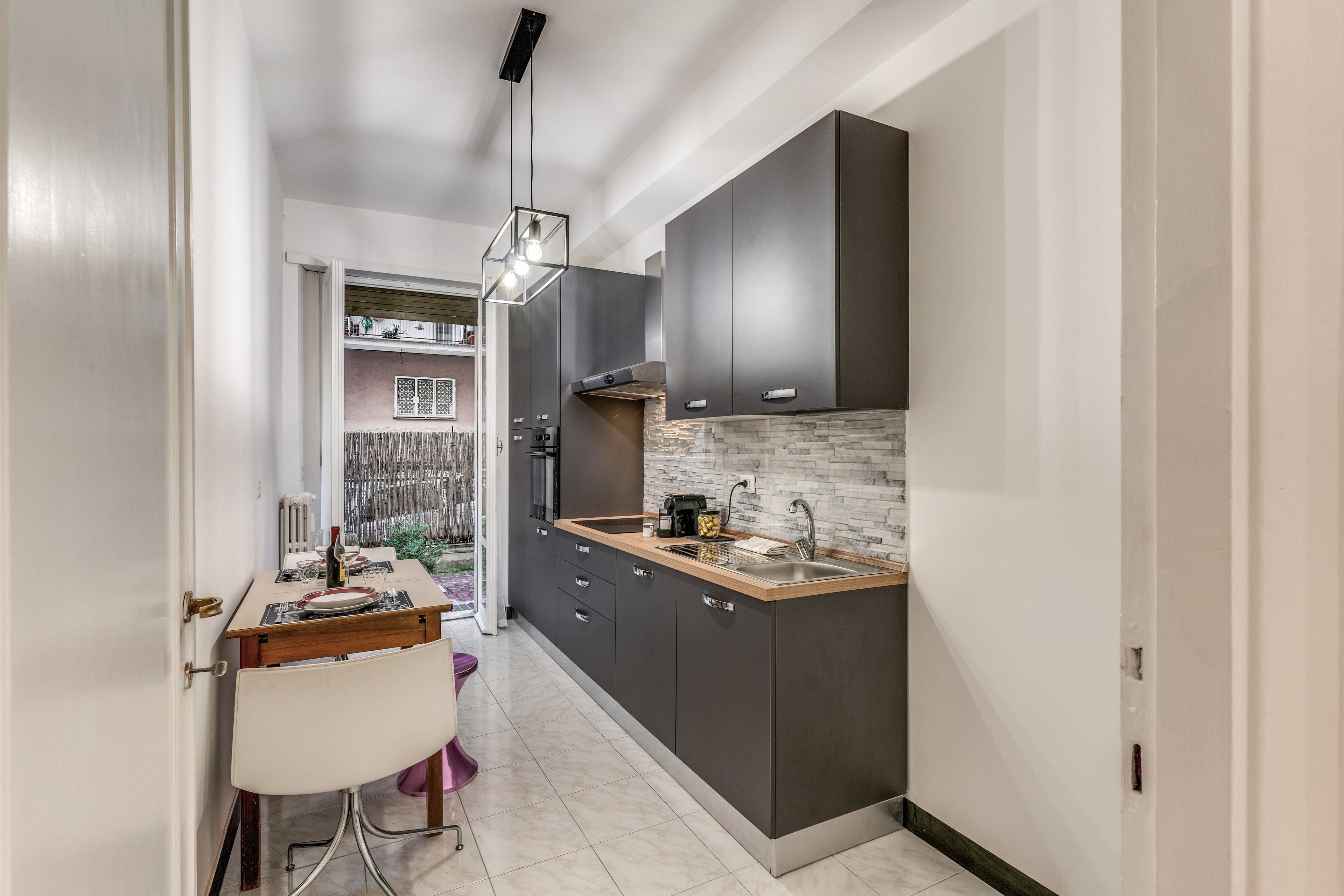 A modern kitchen with dark cabinets, a wooden countertop, and a built-in stove.