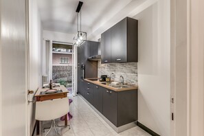 Una cucina moderna con mobili scuri, un piano di lavoro in legno e un piano cottura integrato.