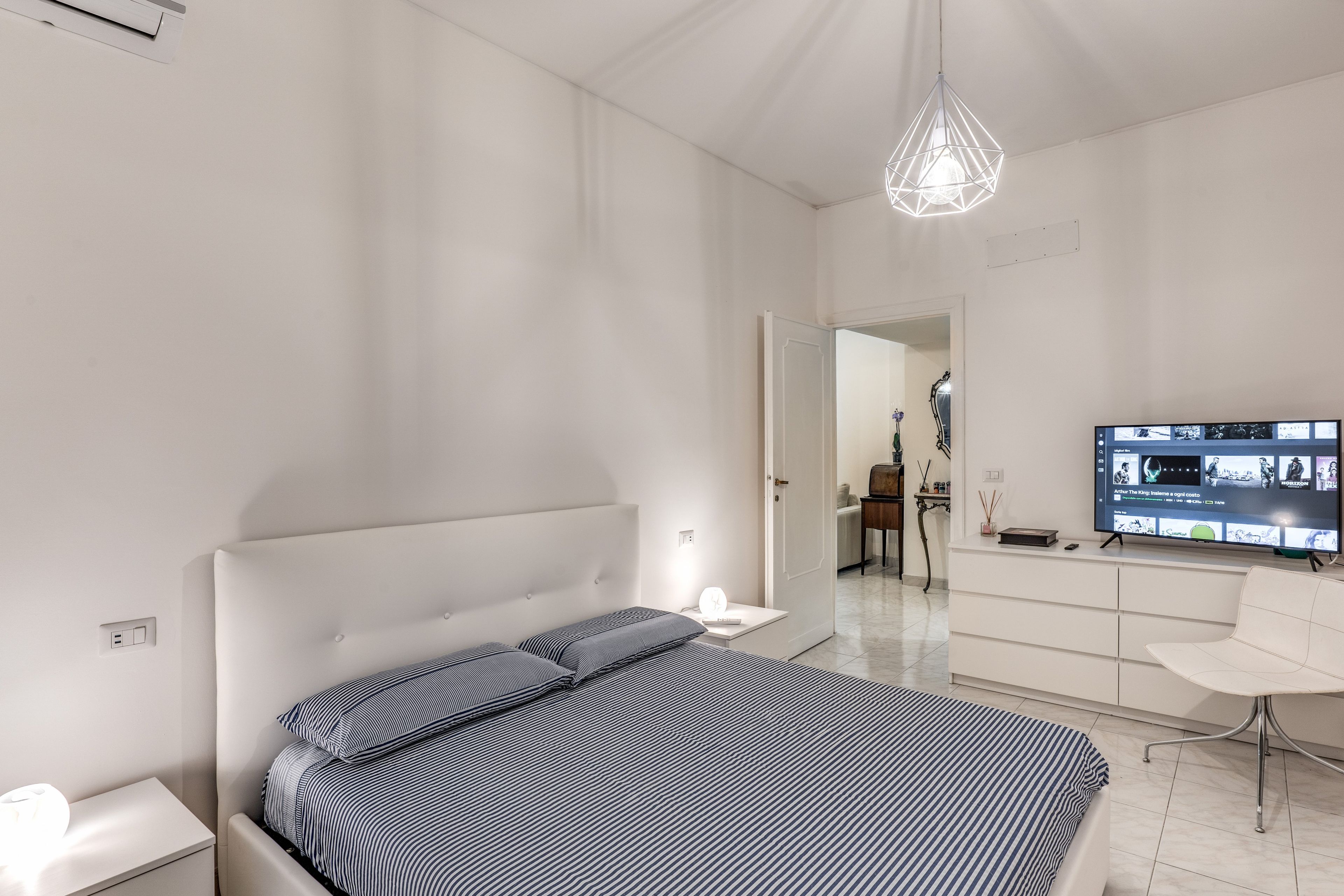 Una camera da letto moderna con un letto, un comodino e una TV su un mobile.