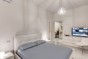 Una camera da letto moderna con un letto, un comodino e una TV su un mobile.