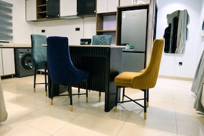 Une cuisine moderne équipée d’une table à manger, de deux chaises, d’un lave-linge et d’un réfrigérateur.