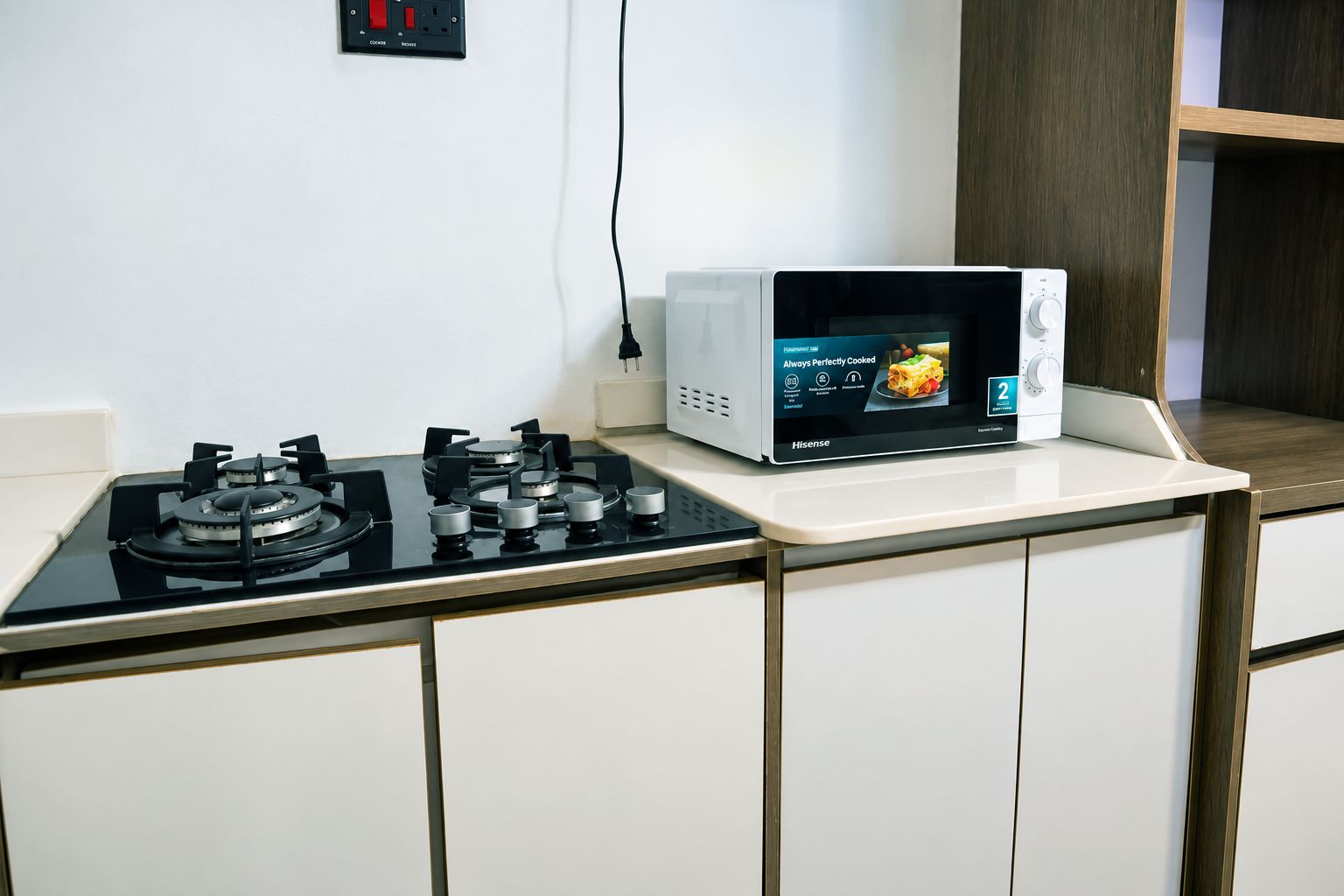 Cozinha com fogão a gás e micro-ondas sobre bancada.