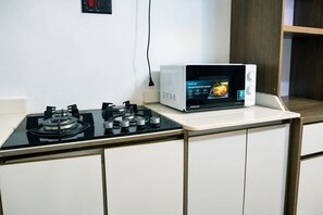 Cozinha com fogão a gás e micro-ondas sobre bancada.