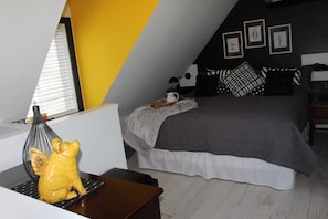 A bedroom with a bed, a desk, a chair, and a decorative yellow pig statue.