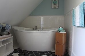 A bathroom with a freestanding bathtub, a small wooden stool, and a towel rack.
