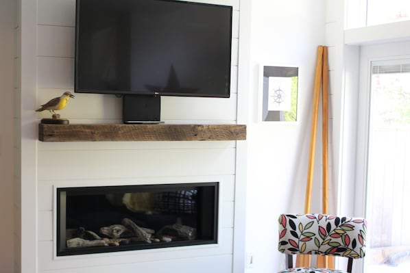 A flat-screen TV mounted on a wooden shelf above a fireplace.