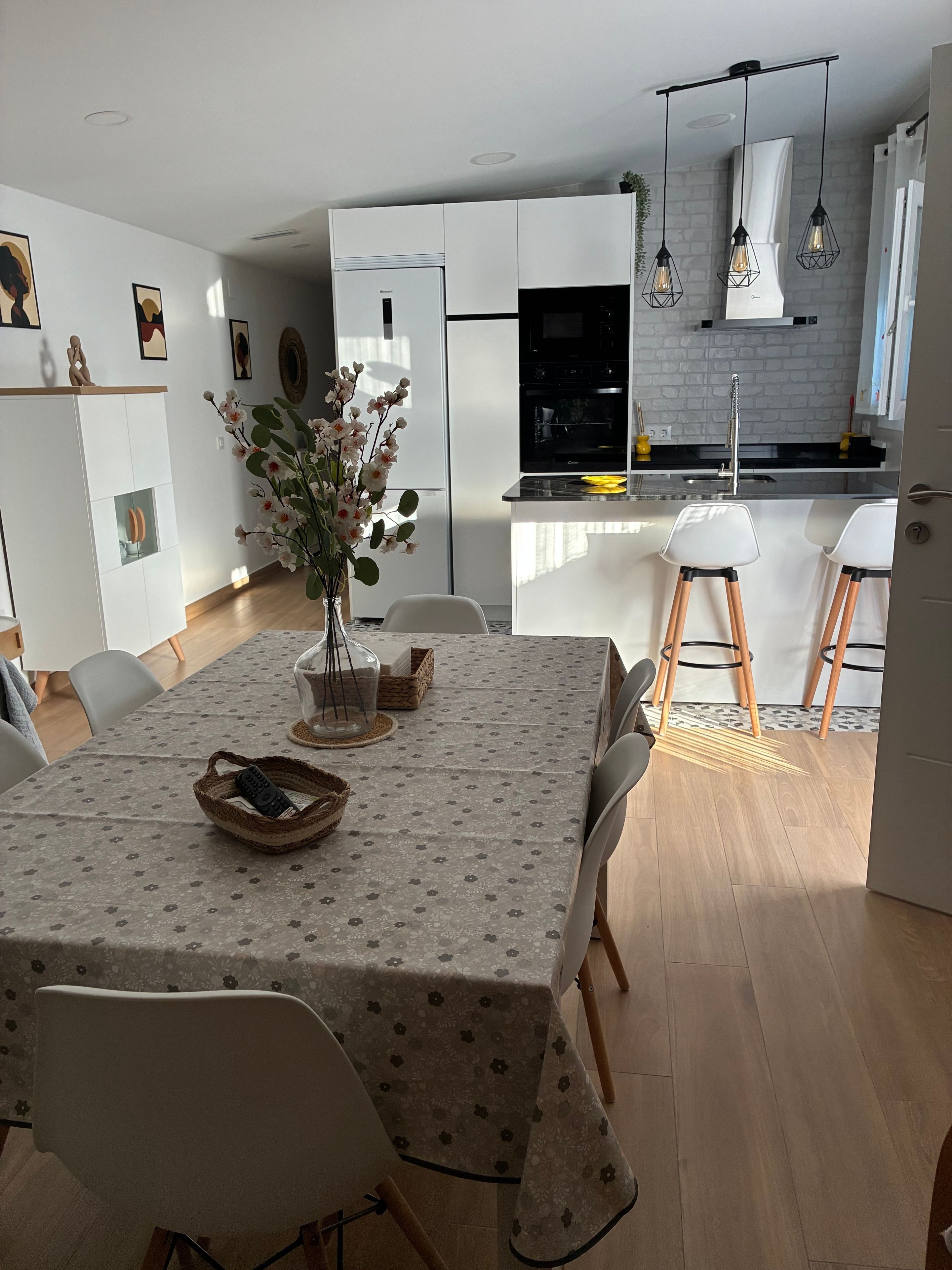 A modern kitchen with white cabinets, a black oven, and a dining area with a table set for two.