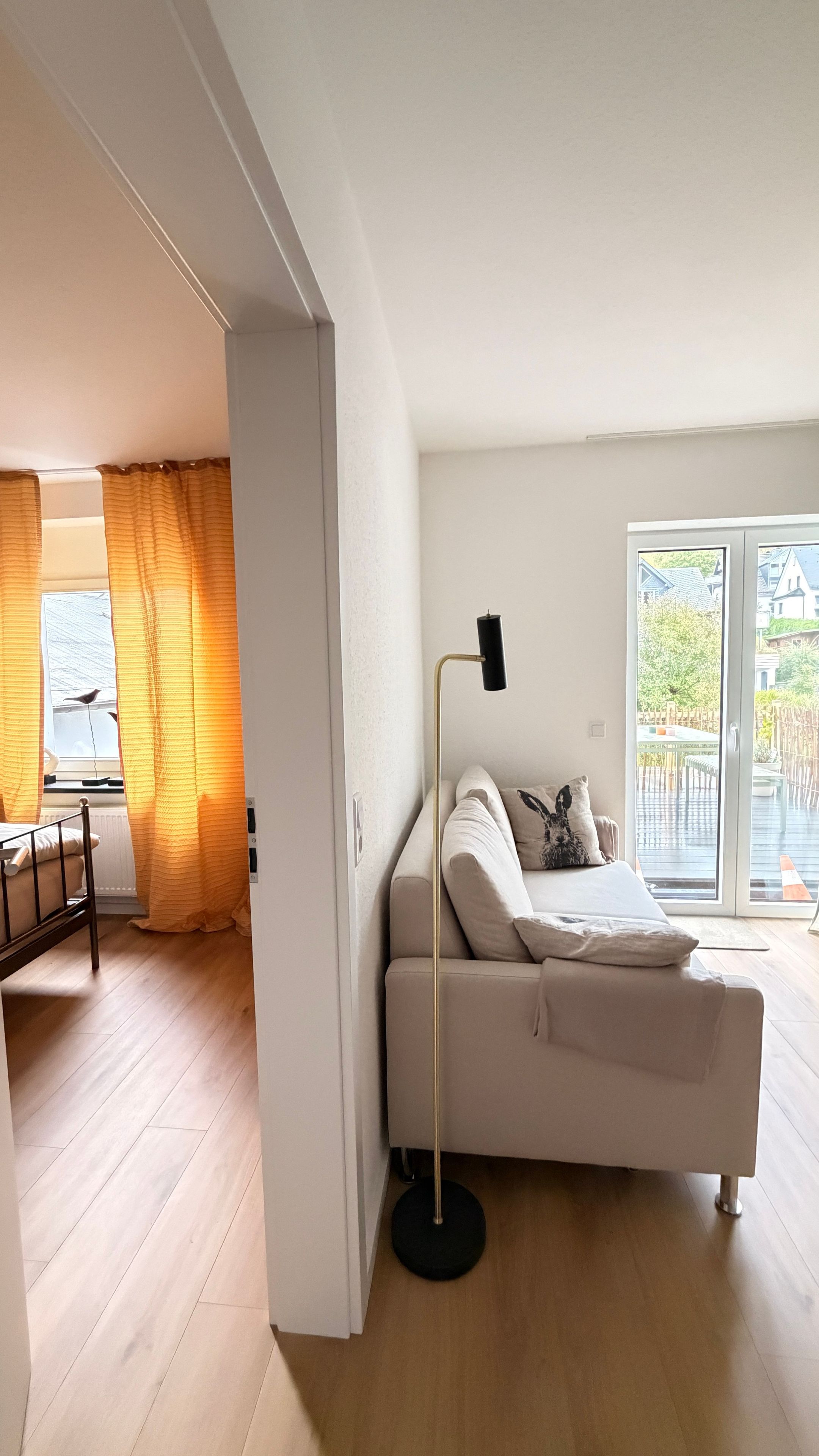 Una camera da letto con un letto, una lampada da terra e vista sull'esterno tramite una porta scorrevole.