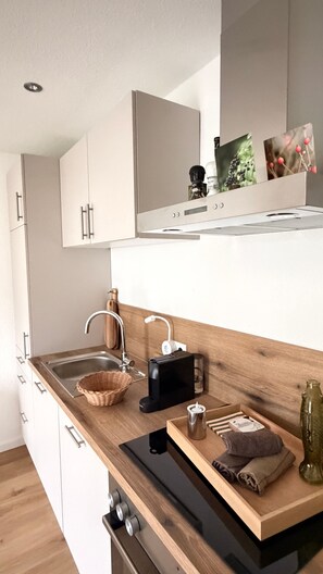 A modern kitchen with a wooden countertop, a built-in sink, and a coffee machine. - Brandenburgs Holiday Apartment Sauerland Ostwig – Deluxe, 50 m² with Private Terrace (Bestwig)