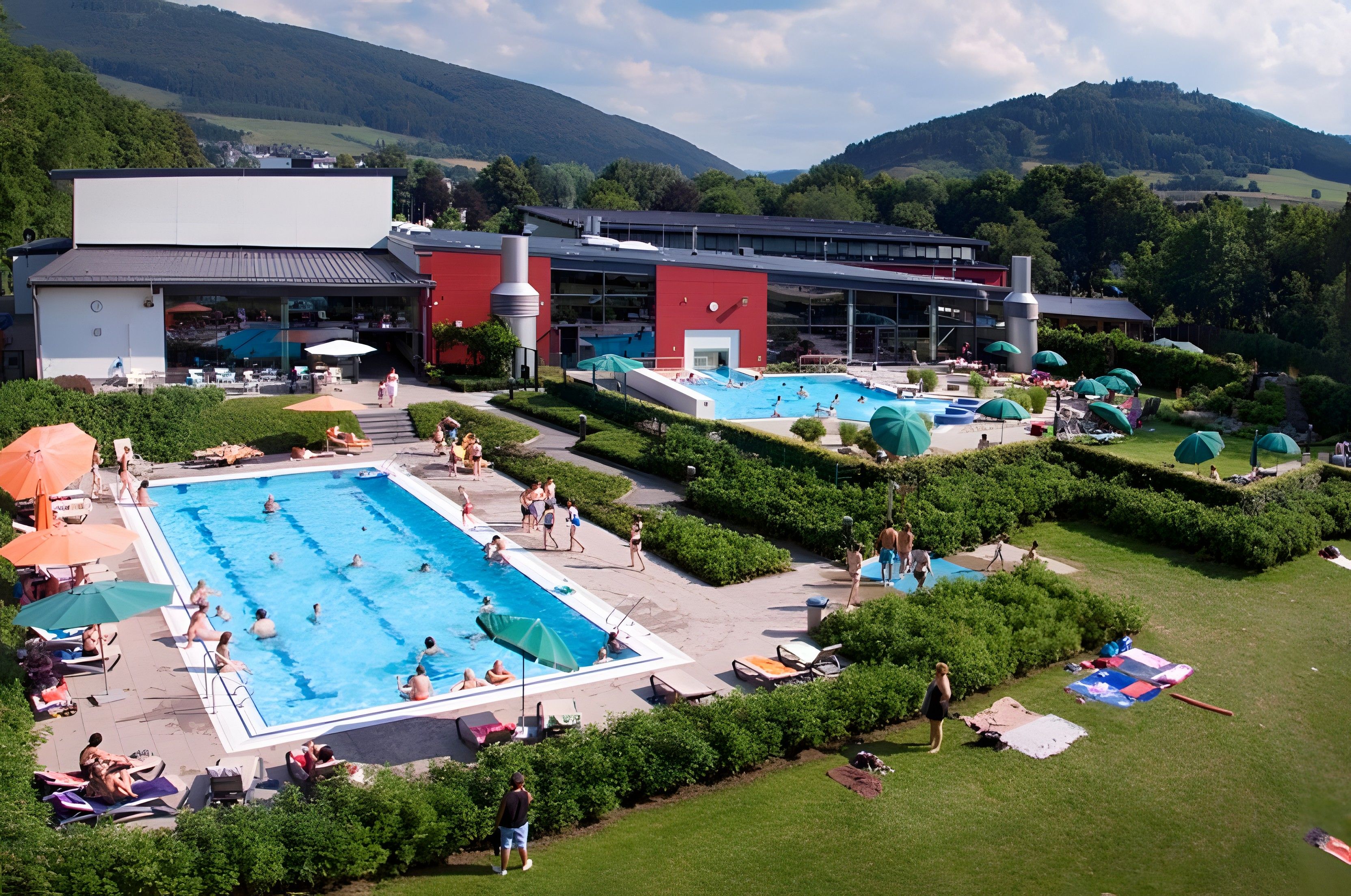 Un hotel con diverse piscine, zone relax all'aperto e montagne sullo sfondo.