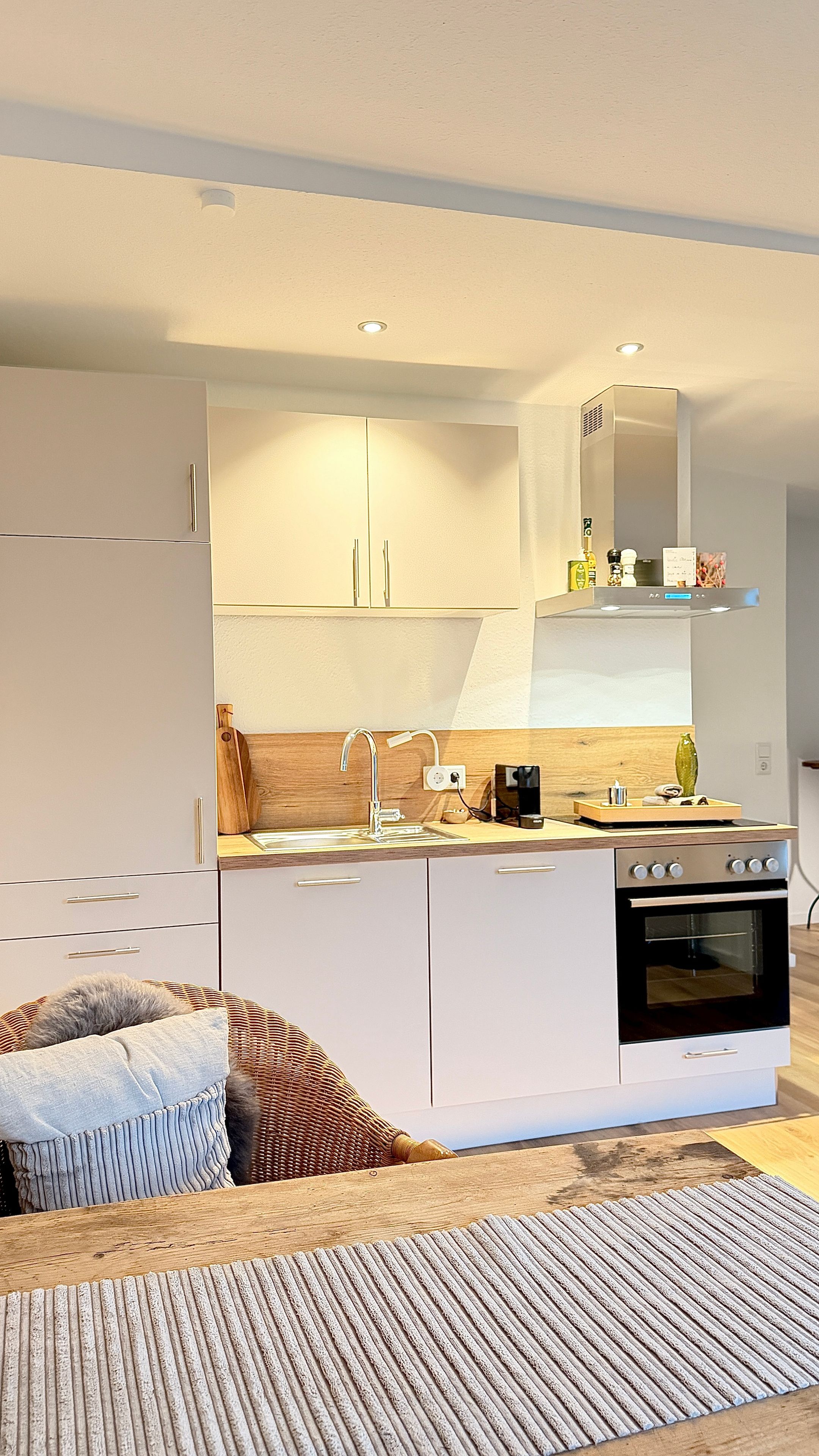 Una cocina moderna con armarios blancos, horno integrado y encimera de madera.