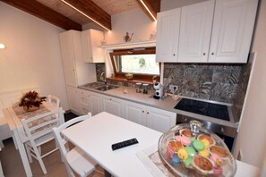 Una cocina con armarios blancos, una ventana sobre el lavamanos y una mesa con sillas.