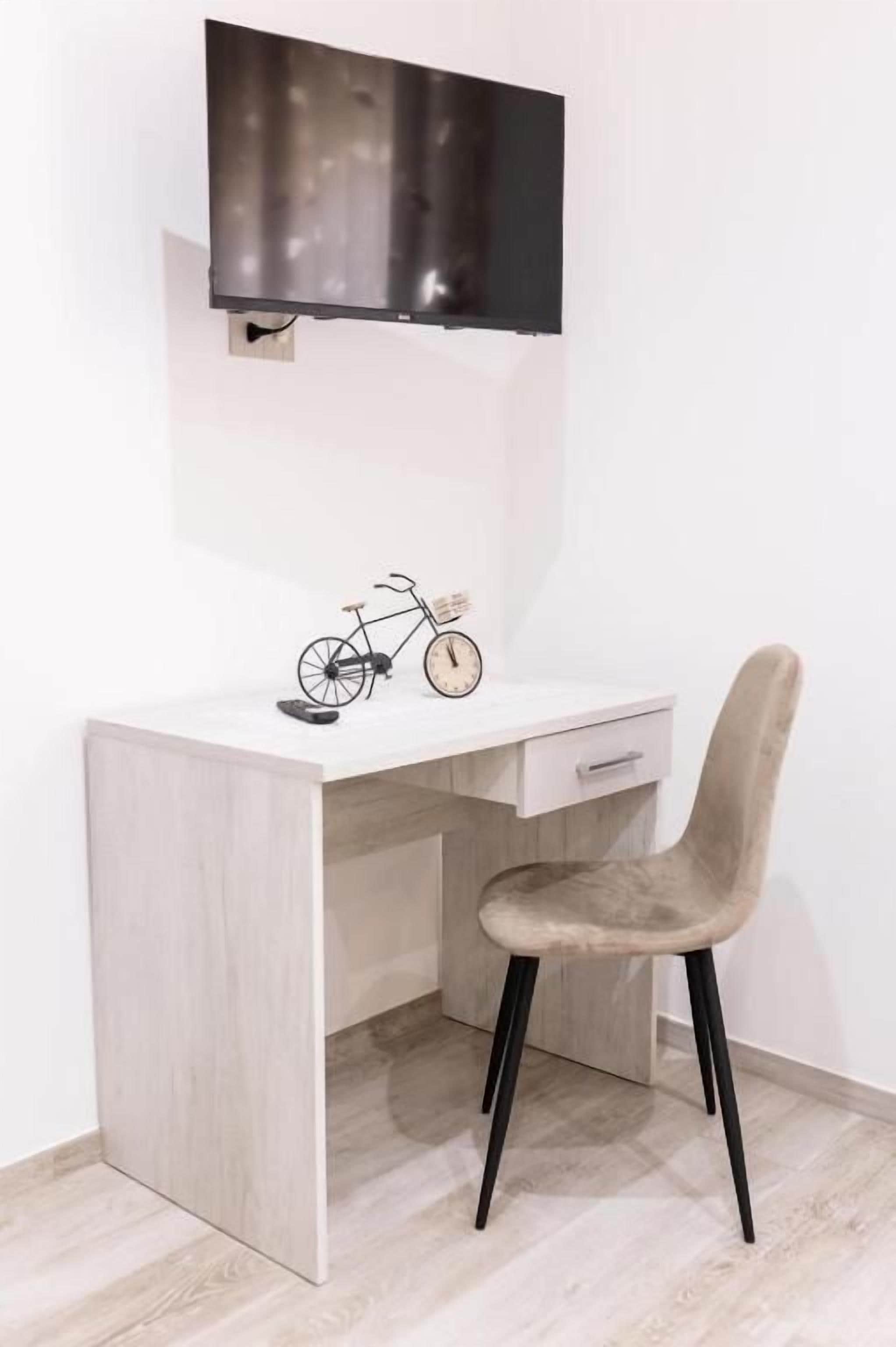 A modern desk with a mounted television, a bicycle, and a chair.