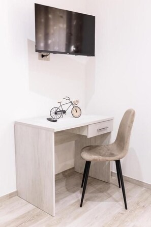 Un escritorio moderno con un televisor montado, una bicicleta y una silla.