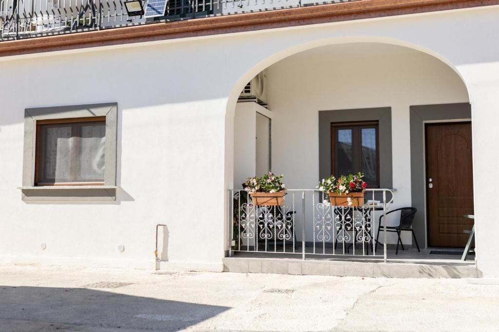 Ein Gebäude mit weißer Fassade, einem Balkon mit Metallgeländern und einer Tür.
