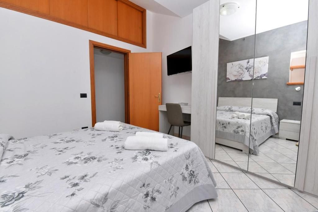 A bedroom with a bed, a desk, and a mirror.