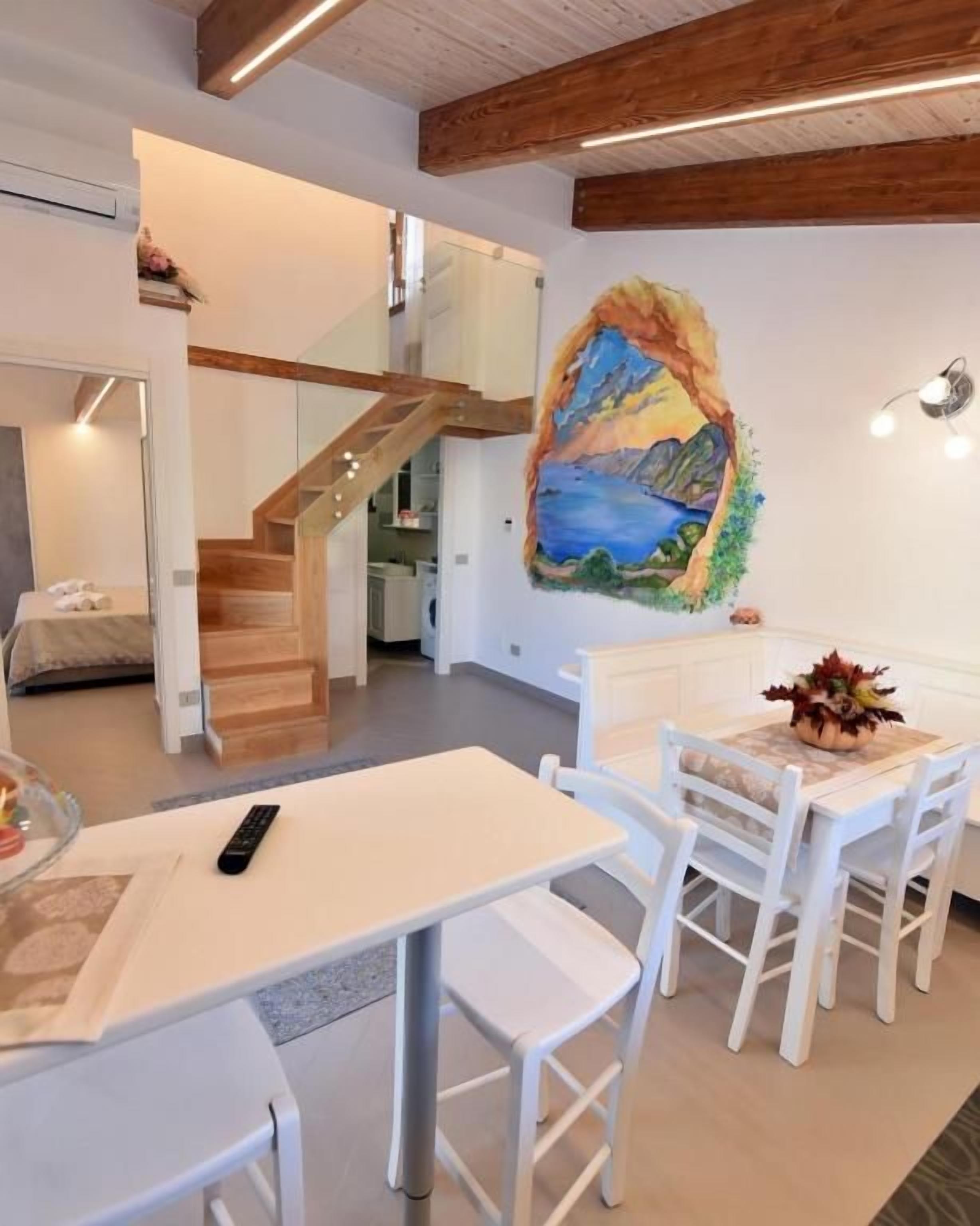 Ein Essbereich mit Tisch und Stühlen, einem Gemälde an der Wand und einer Treppe, die in ein Obergeschoss führt.