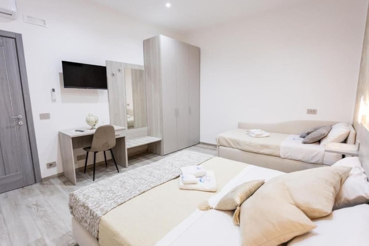 A modern bedroom with a bed, a desk, a chair, and a wardrobe.