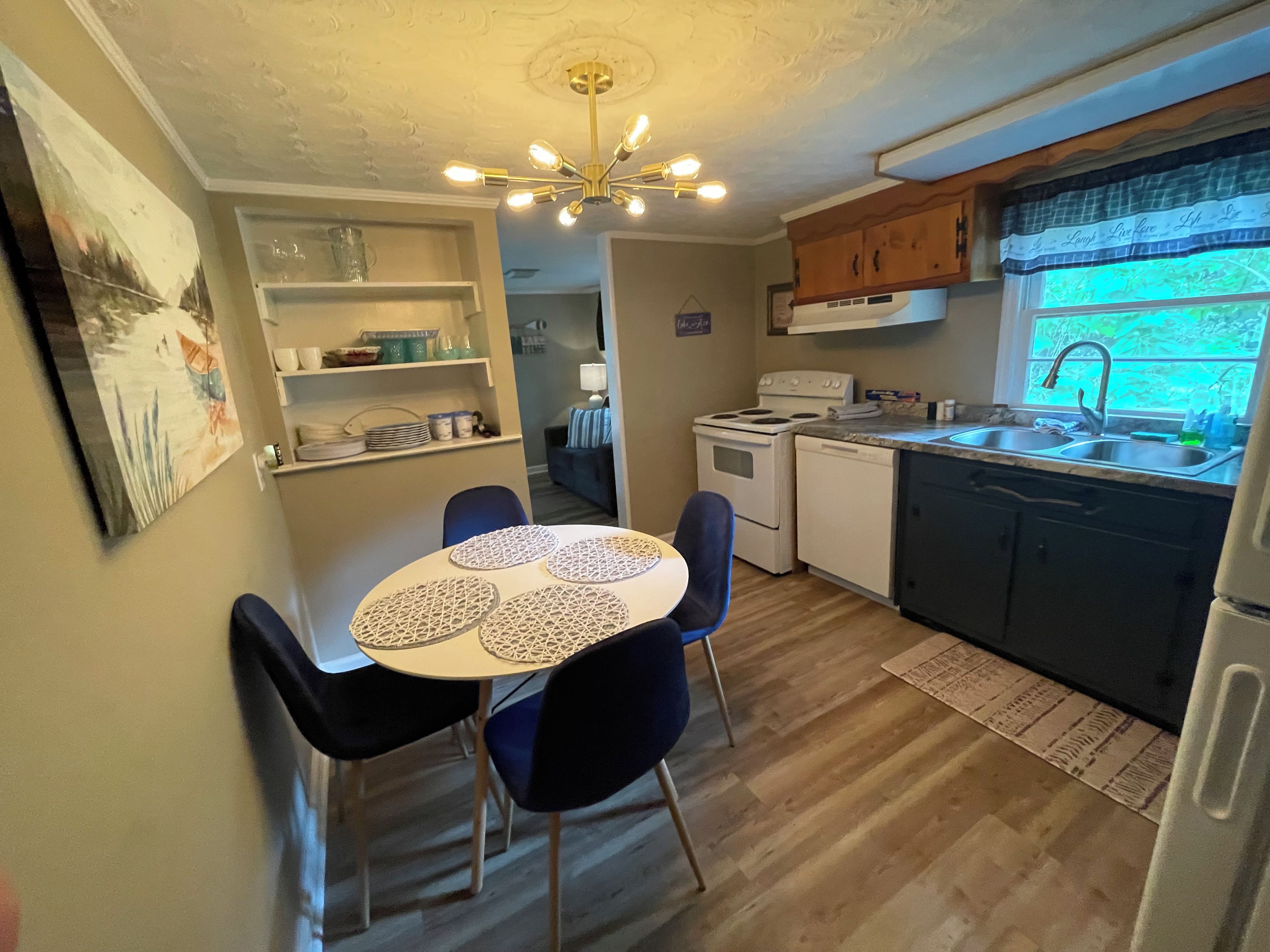A compact kitchen with a dining area, featuring a central island, a stove, and a sink.