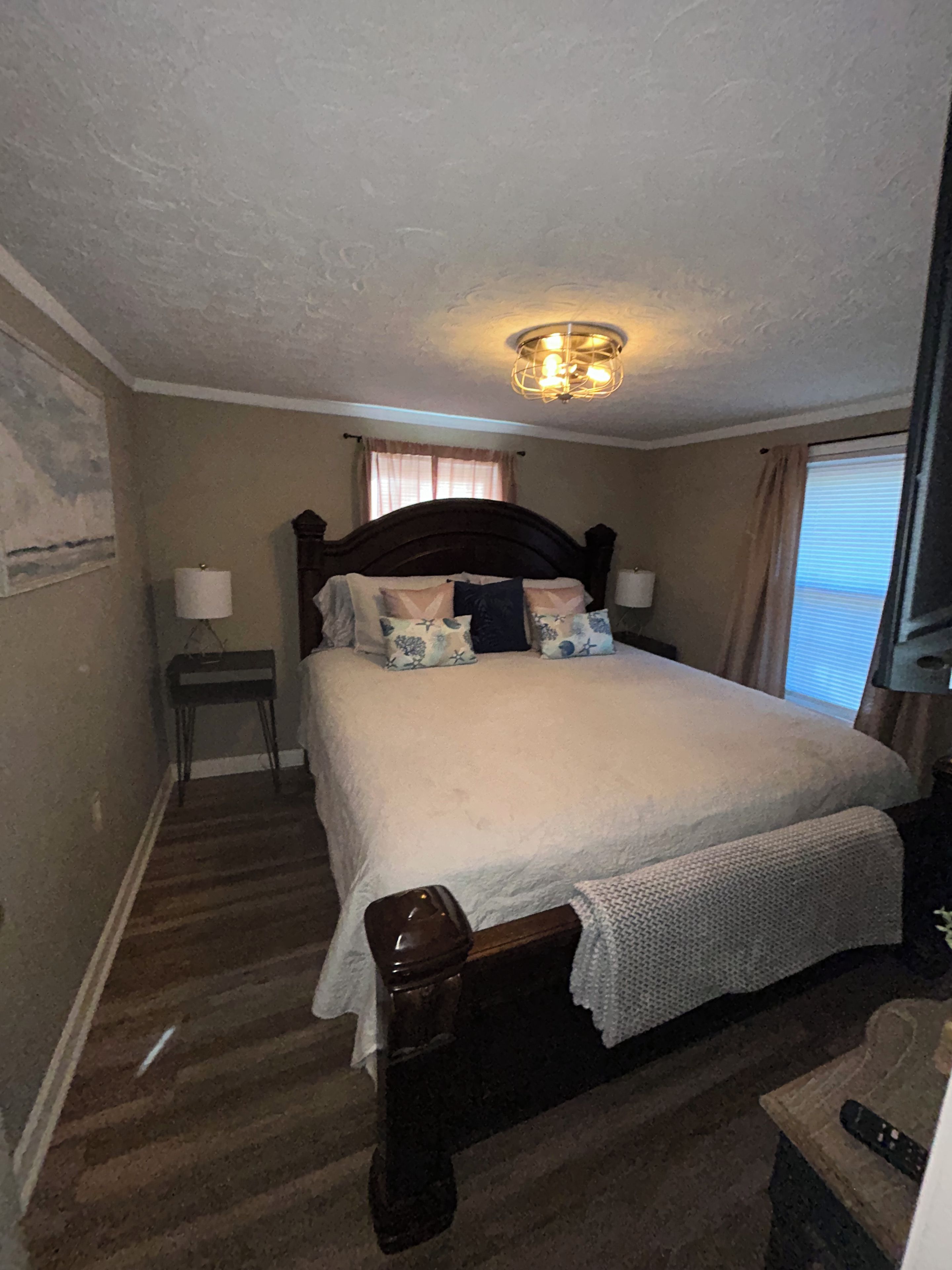 A bedroom with a large bed, a bedside table, a lamp, and a ceiling light fixture.