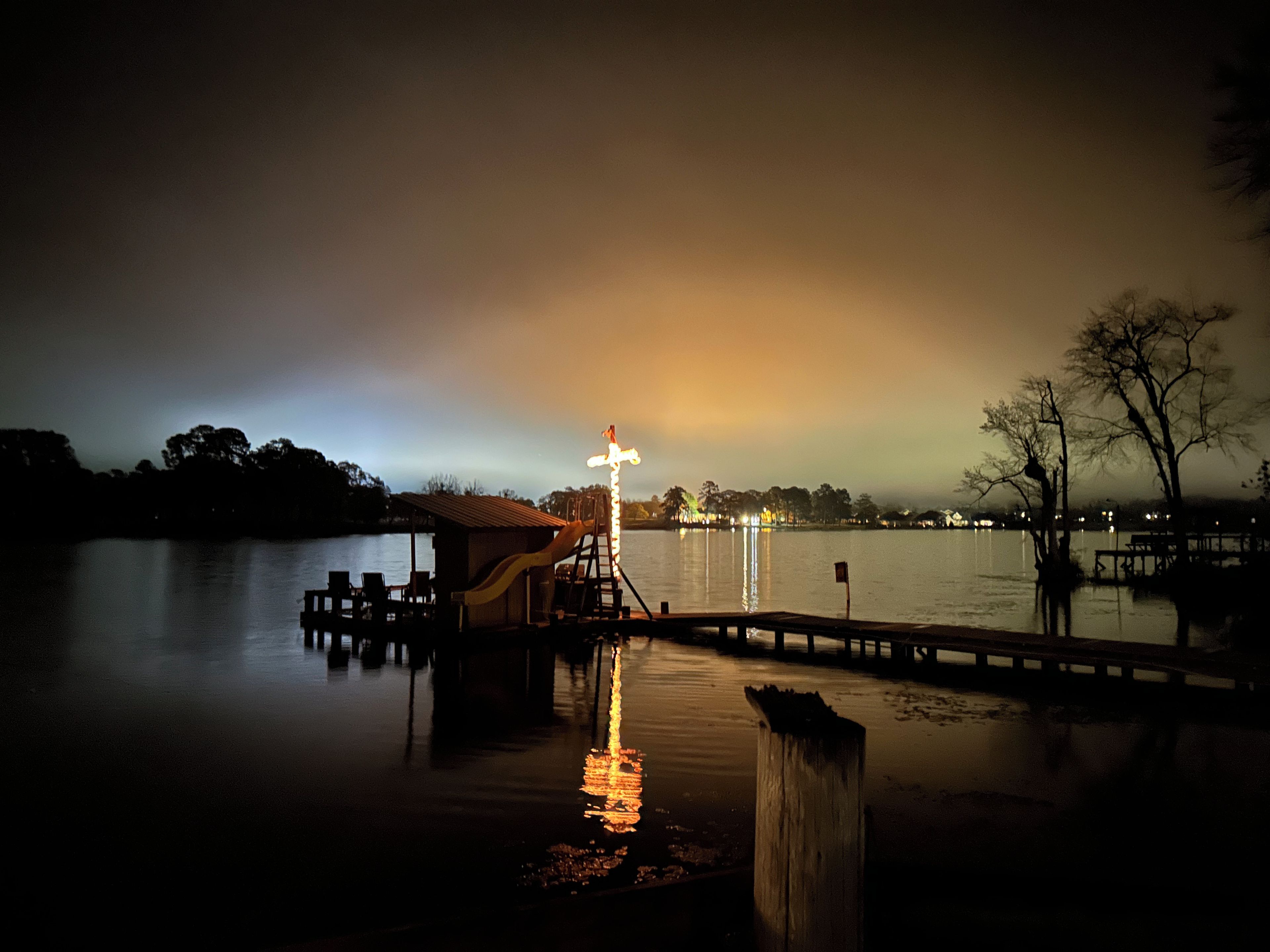 A dock extending into calm water with a small building and a slide.