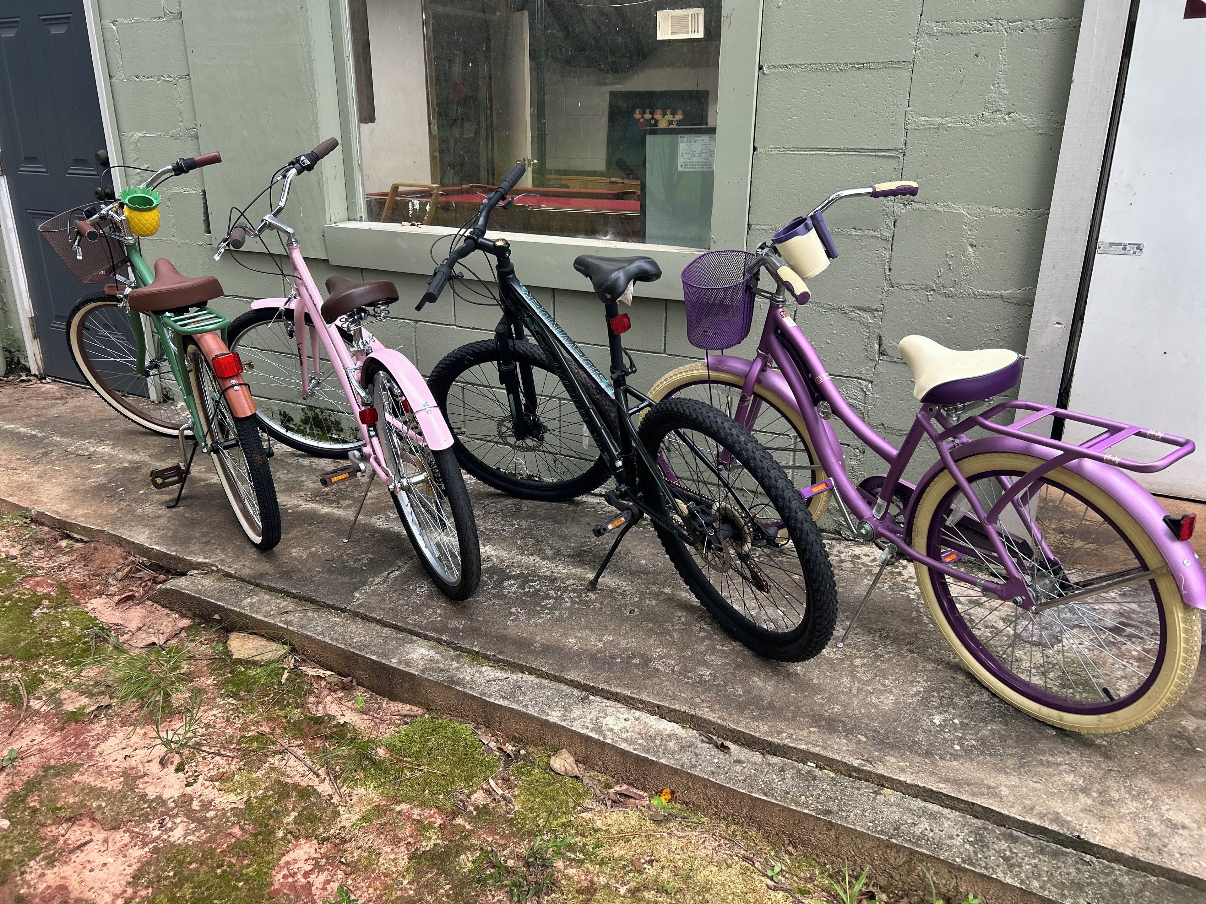 Three bicycles parked on a concrete surface next to a building.