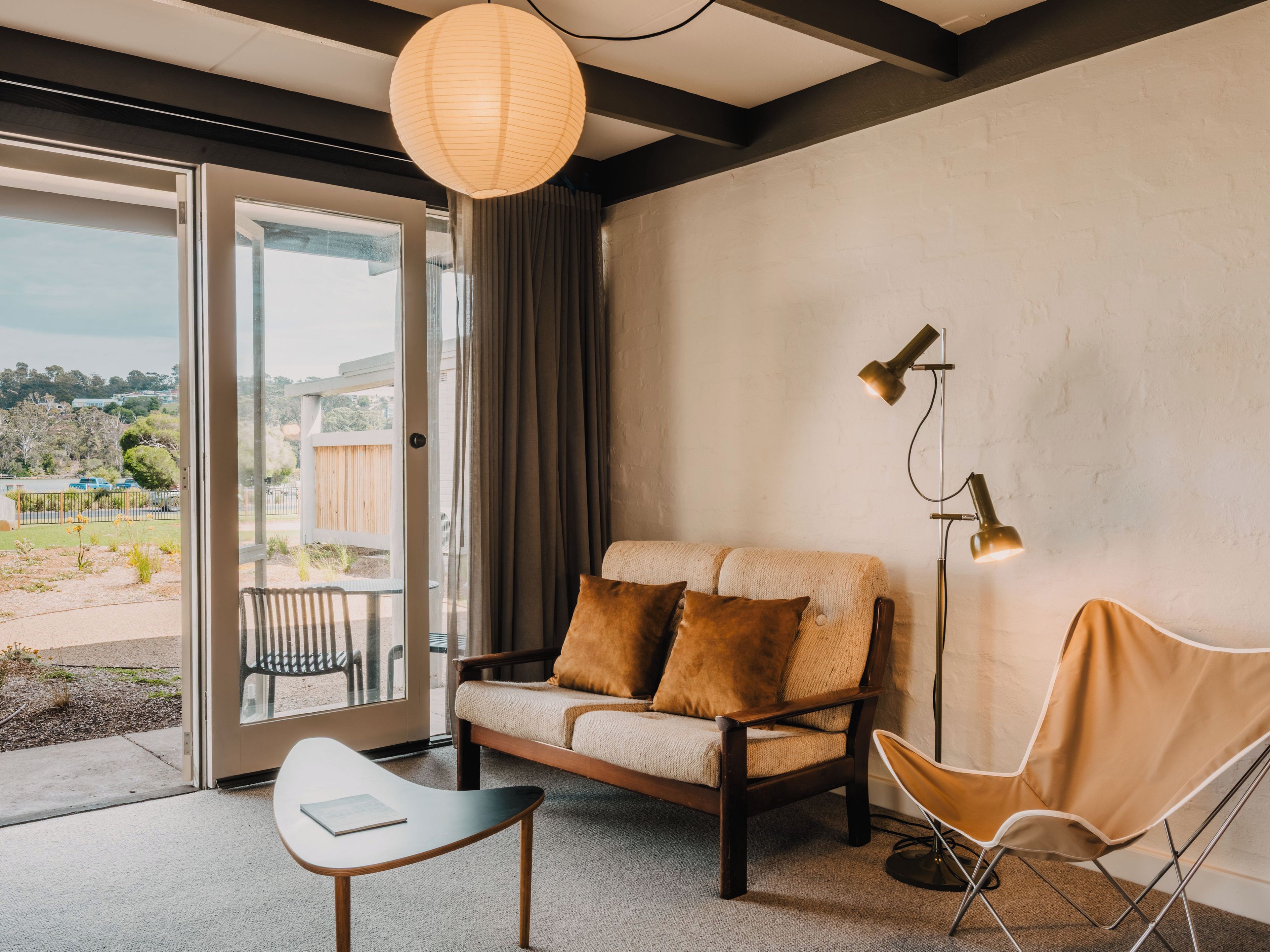 A modern living room with a sofa, a chair, a table, and a floor lamp.