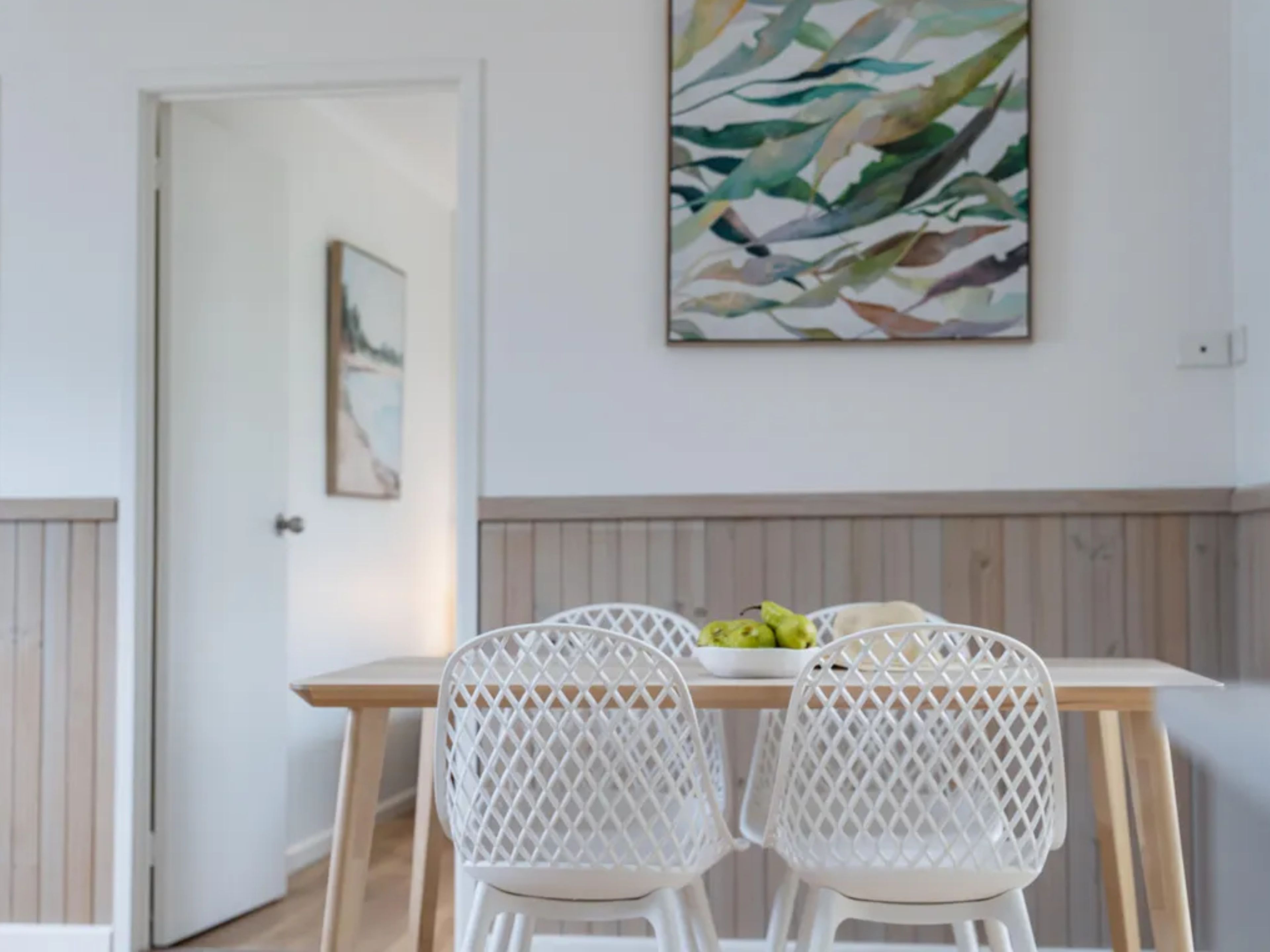 Een eetgedeelte met een houten tafel en witte stoelen met een ruitpatroon.