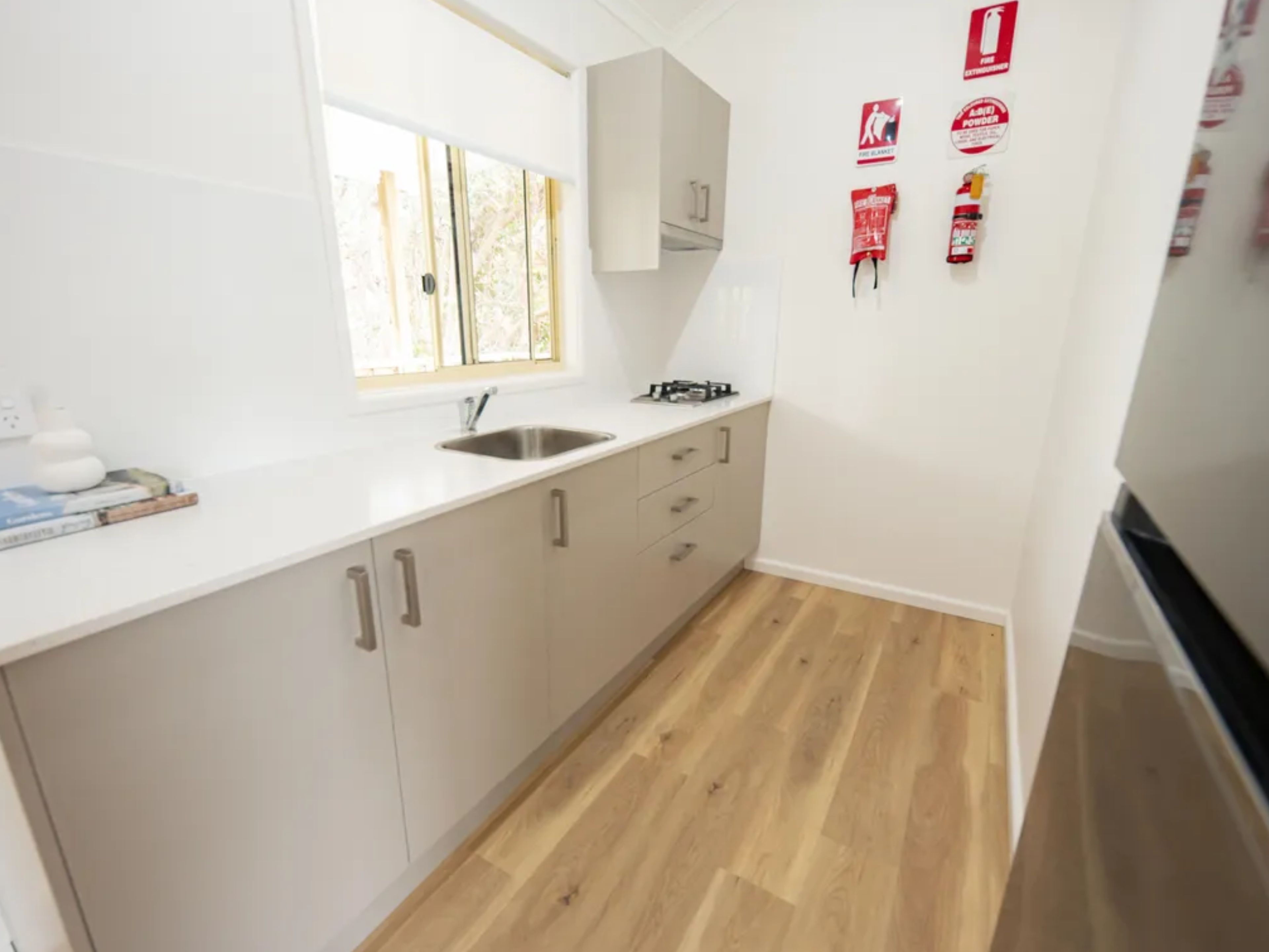 A kitchen with a window, white cabinets, a sink, and a stove.