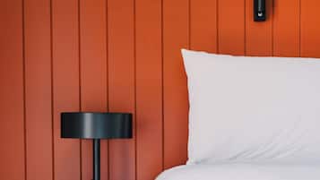 A bed with white bedding against a wall with vertical paneling.