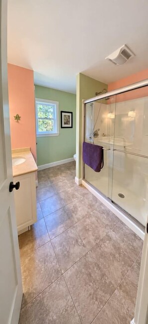 A bathroom with a glass shower enclosure, a sink, and a window. - Spacious 4BR/4BA York Retreat w/ Big Backyard (York)