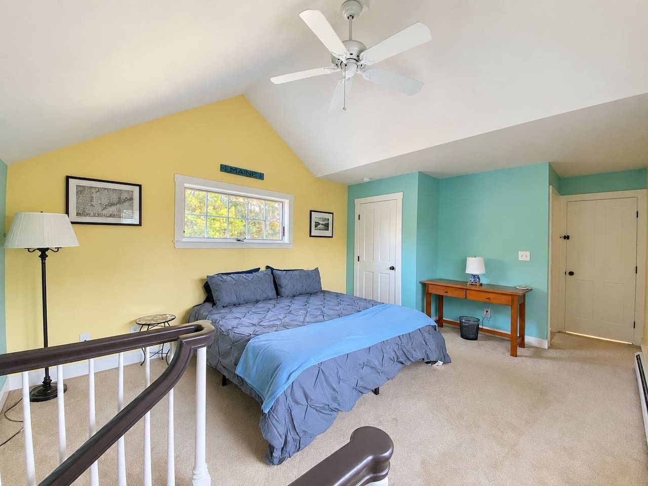 Une chambre à coucher comprenant un lit, un bureau, une chaise, une lampe et un ventilateur de plafond.