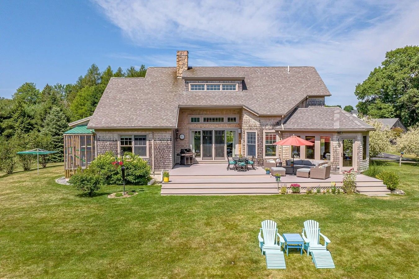 A two-story house with a patio, outdoor seating, and a covered area.