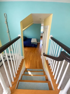 Un escalier menant à une chambre à coucher qui contient un lit, une fenêtre et une porte.
