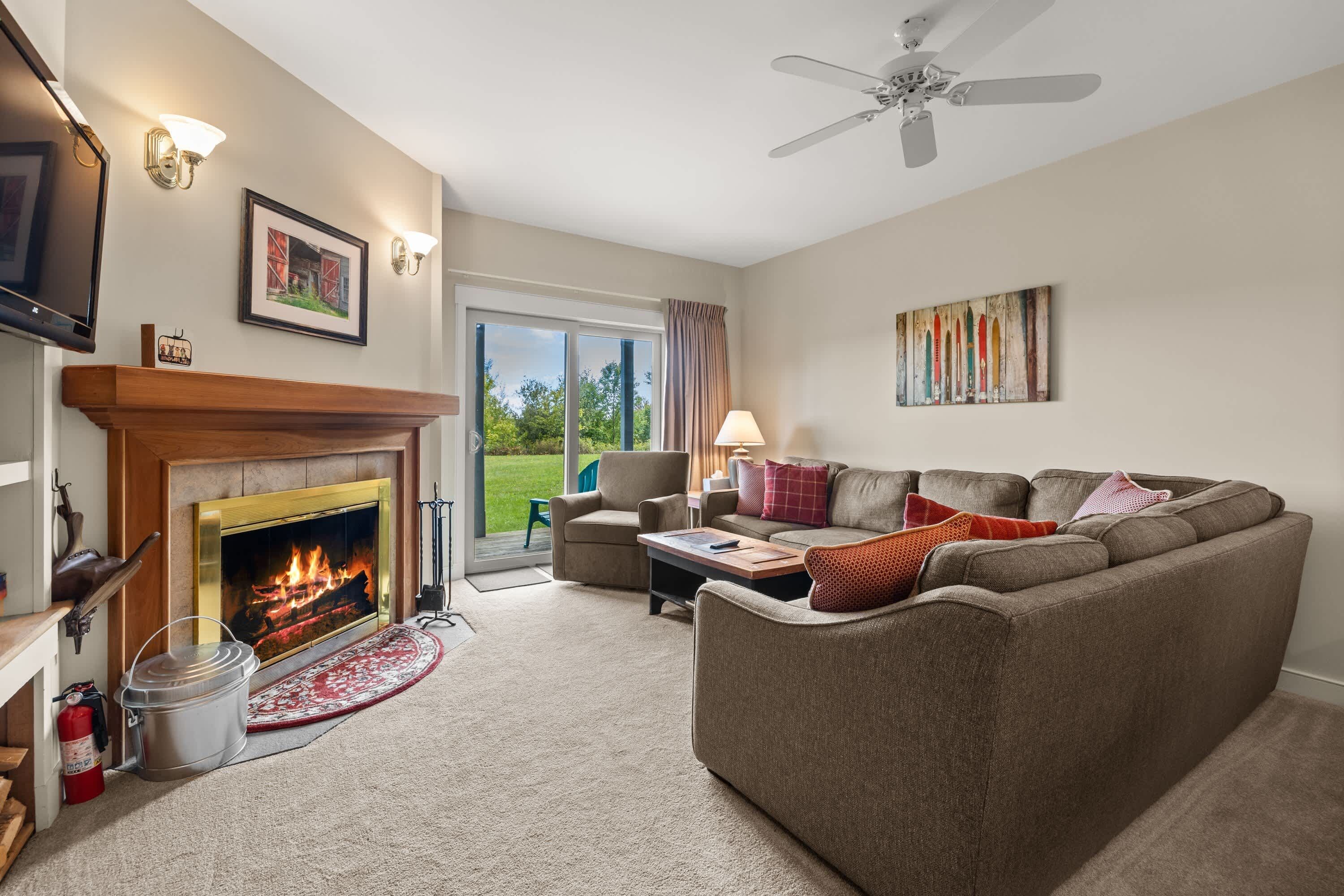 A living room with a fireplace, a sofa, a television, and a ceiling fan.