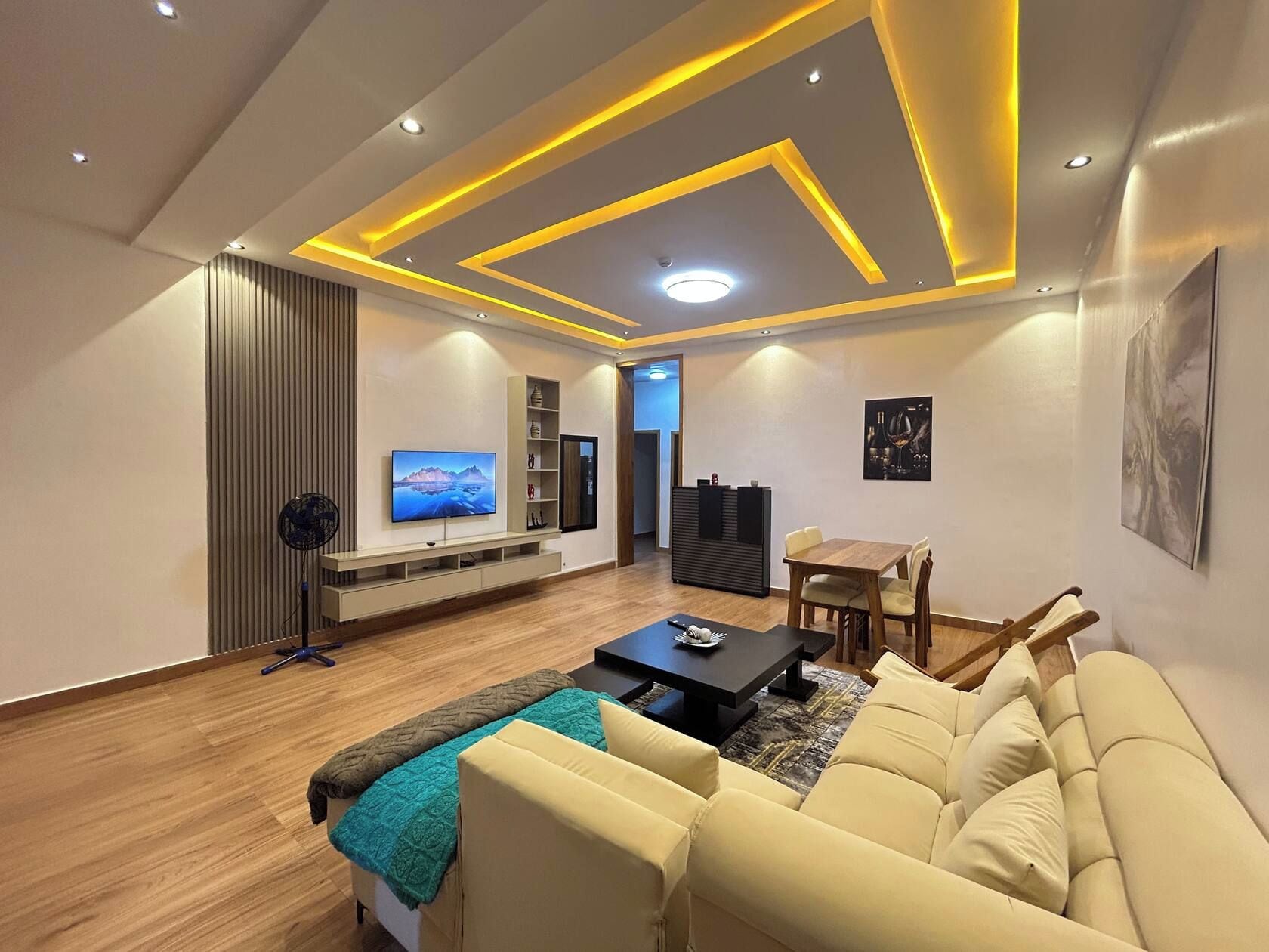 A modern living room with a sofa, a coffee table, a TV, and a dining area.