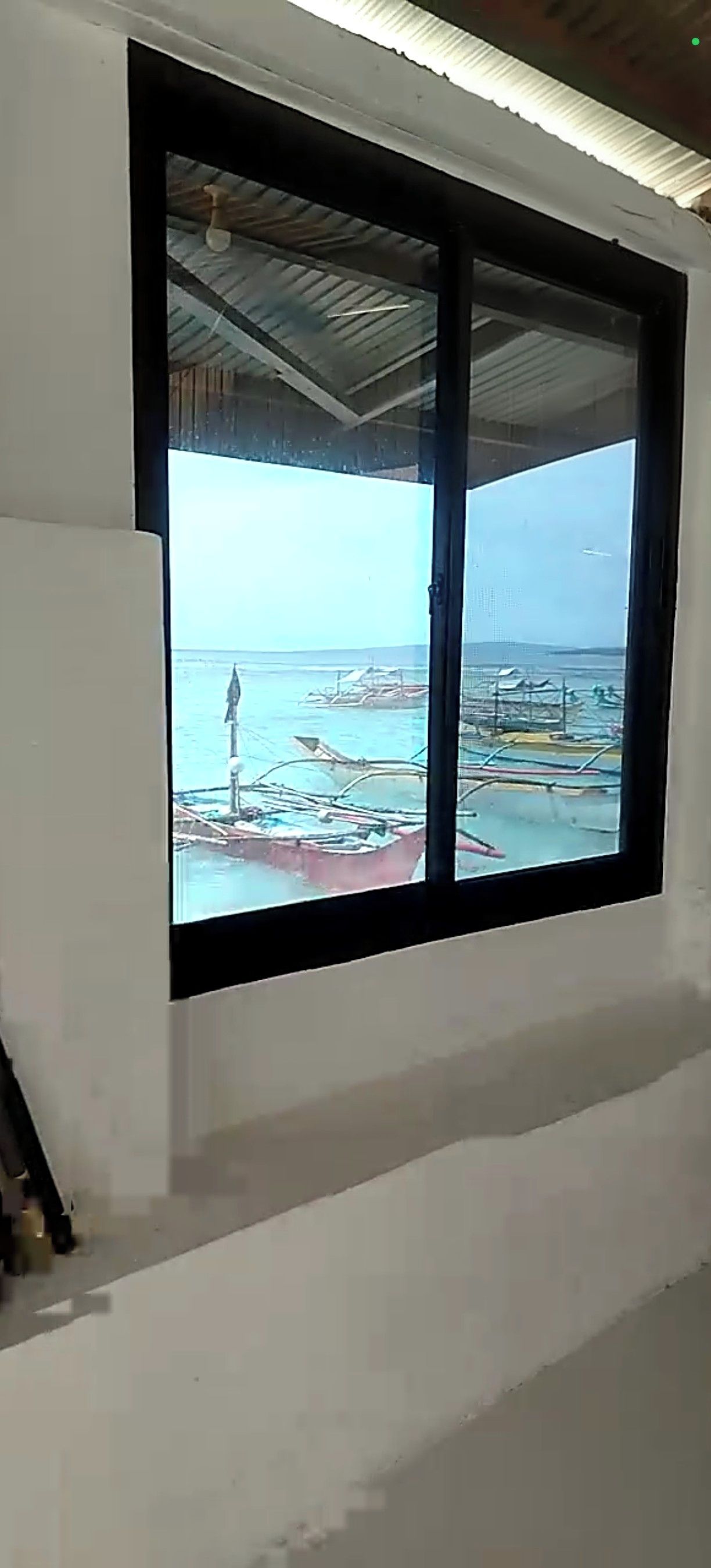 A room with a large window overlooking a body of water with boats.