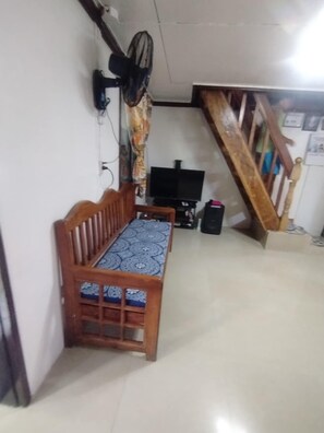 A room with a wooden bench, a television, and a staircase. - GUMOBAO STAYCATION HOUSE (Baganga)