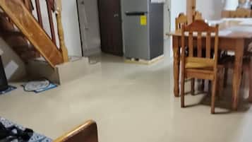 Ein Essbereich mit Holztisch und Stühlen, einem Kühlschrank und einer Treppe, die in einen anderen Raum führt.
