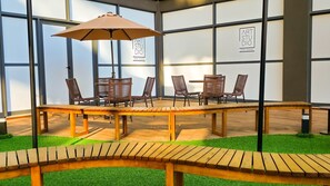 An indoor space with a wooden table and chairs, a large umbrella, and a sign reading 'ART STUDIO'. - New Listing (Salvador)