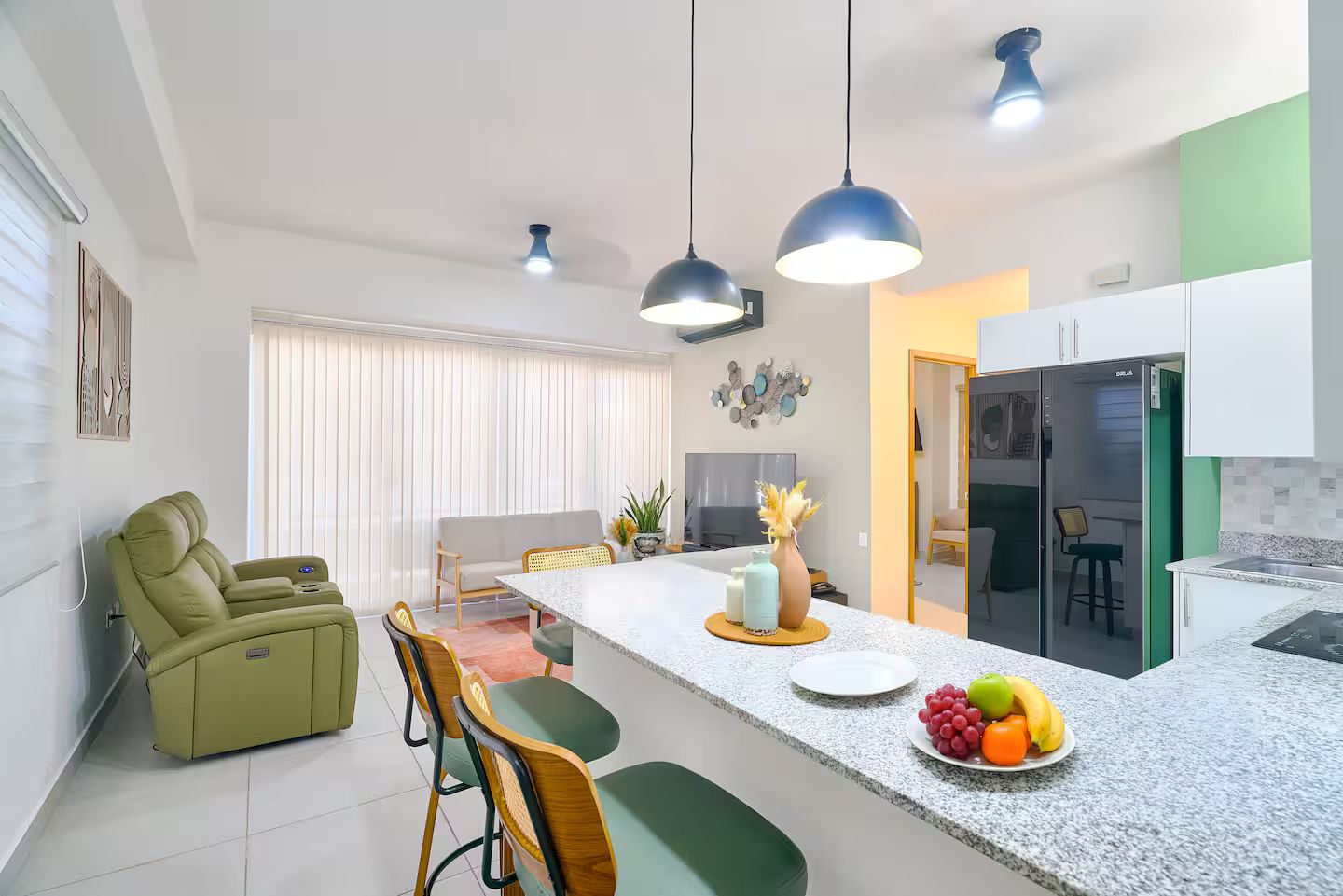 A modern kitchen with a central island, dining area with chairs, and a sofa.