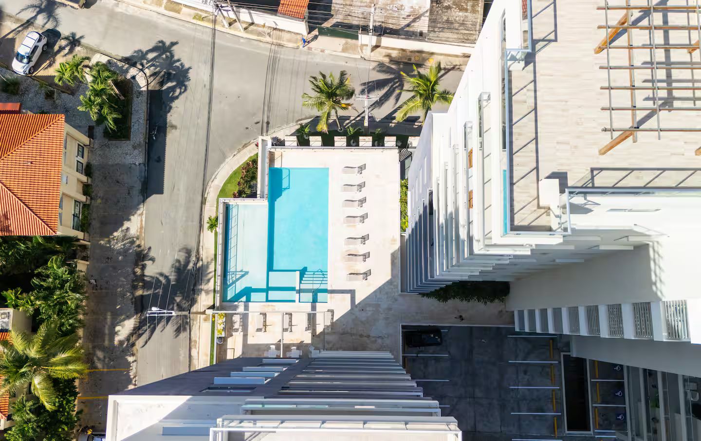A rooftop pool with multiple lounge chairs and a clear view of the surrounding urban area.