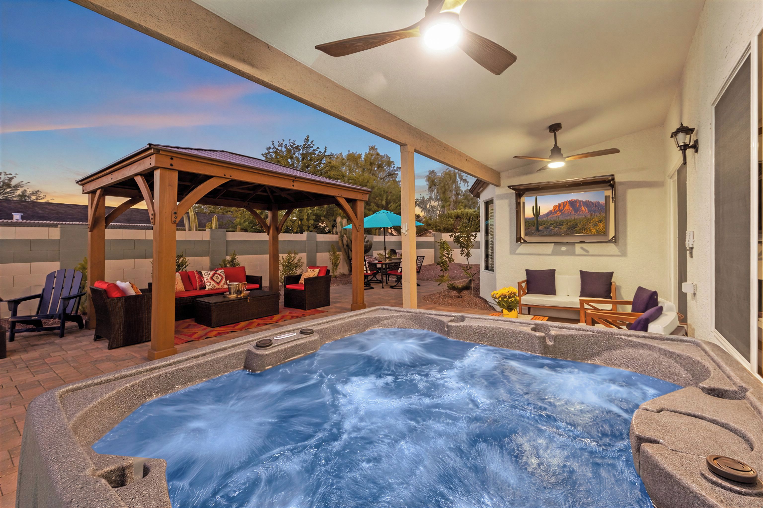 A hot tub area with a pergola, seating, and a view of a mountain through a window.
